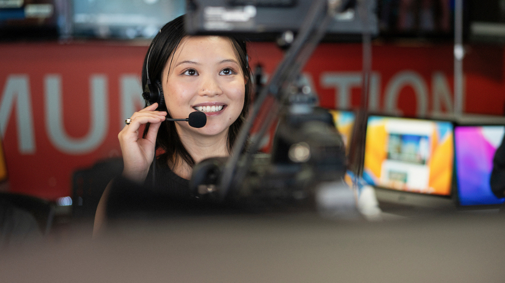 Студент Лойолы улыбается в Convergence Studio Школы коммуникаций