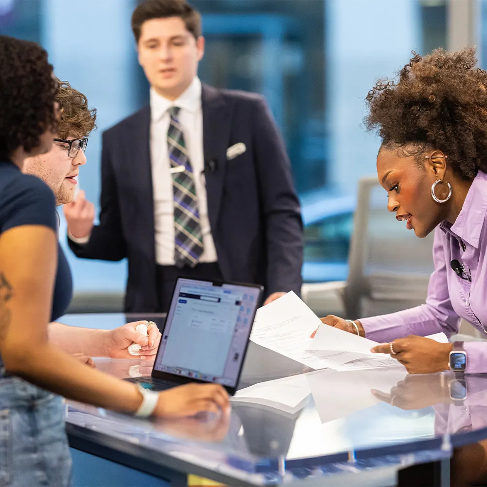 Students collaborating at the news desk in the convergence studio