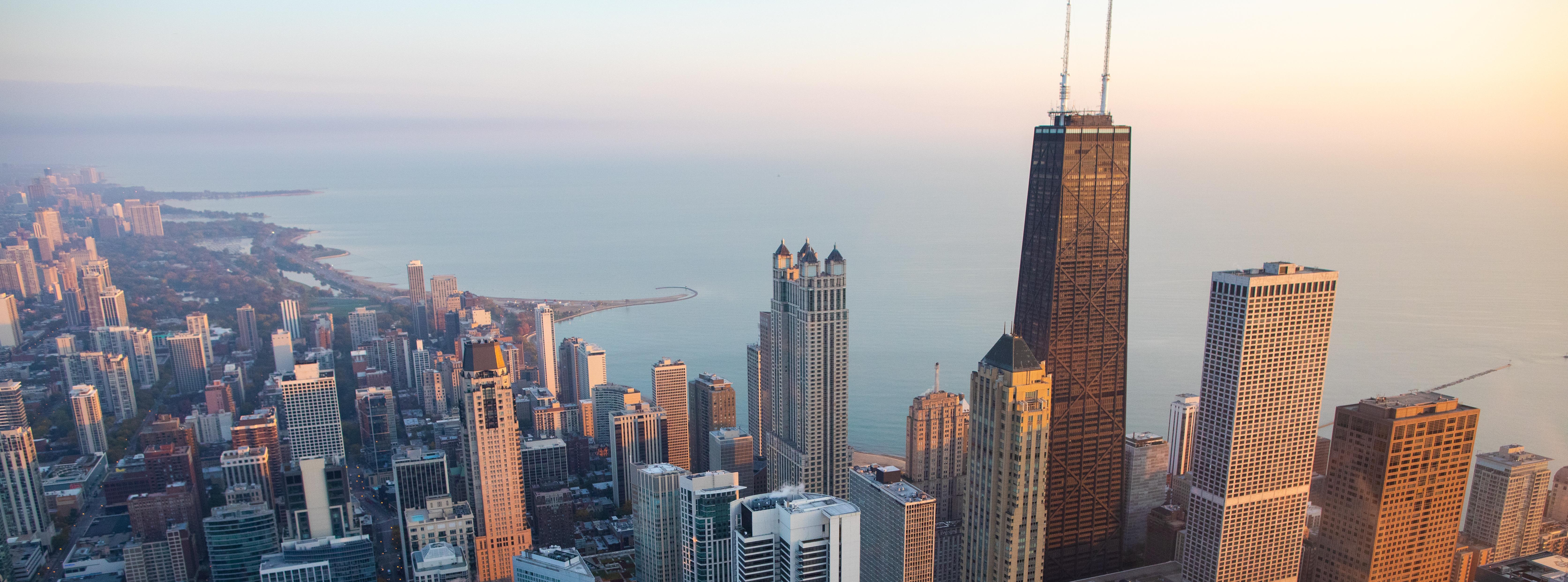 An aerial view of Chicago with Lake Michigan in the background during sunset.