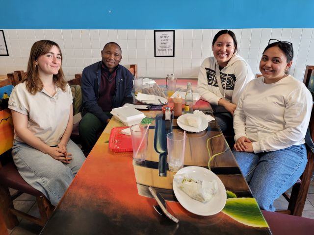Four students, three women and one man, working together at a classroom table with data
