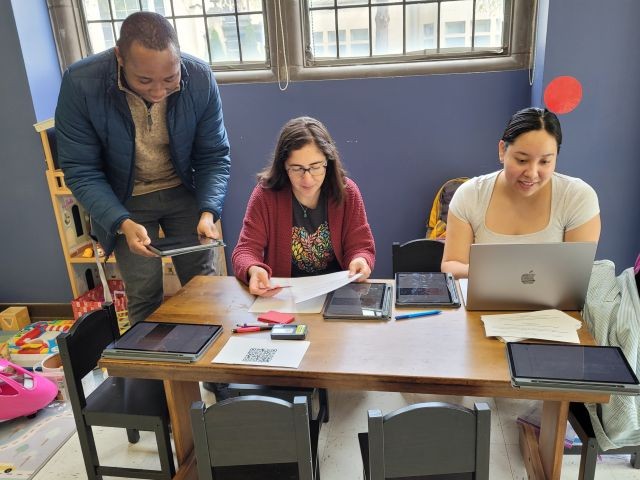 Three people working on research at a table, one man and two women