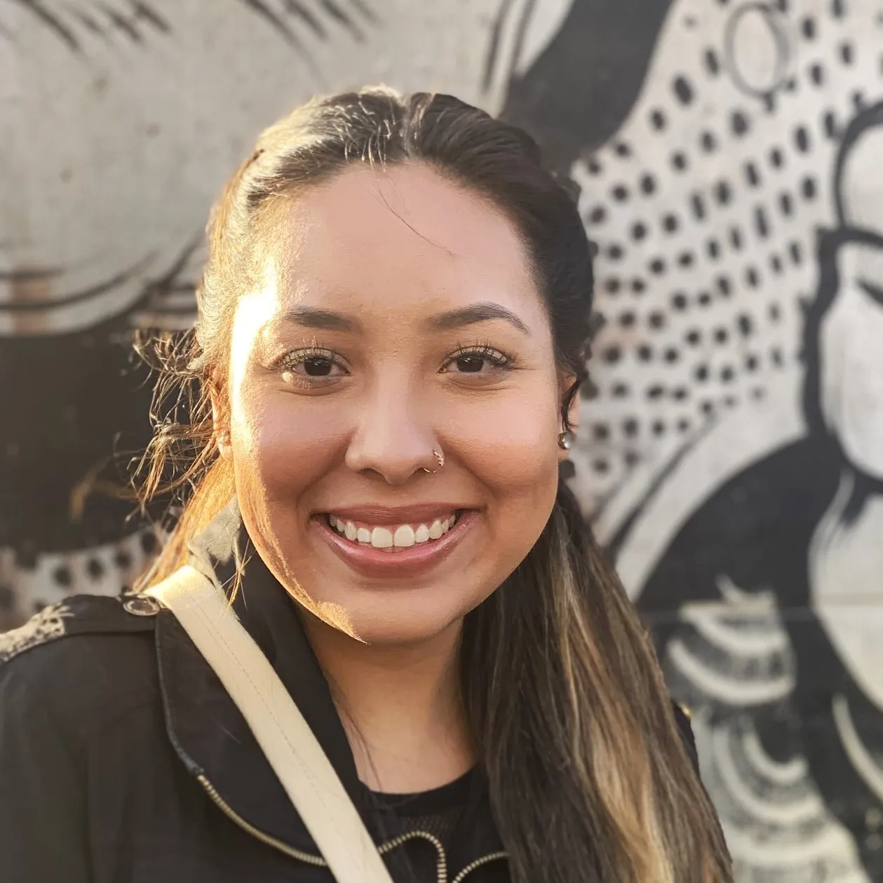 Young woman with dark hair posing outdoors and smiling 
