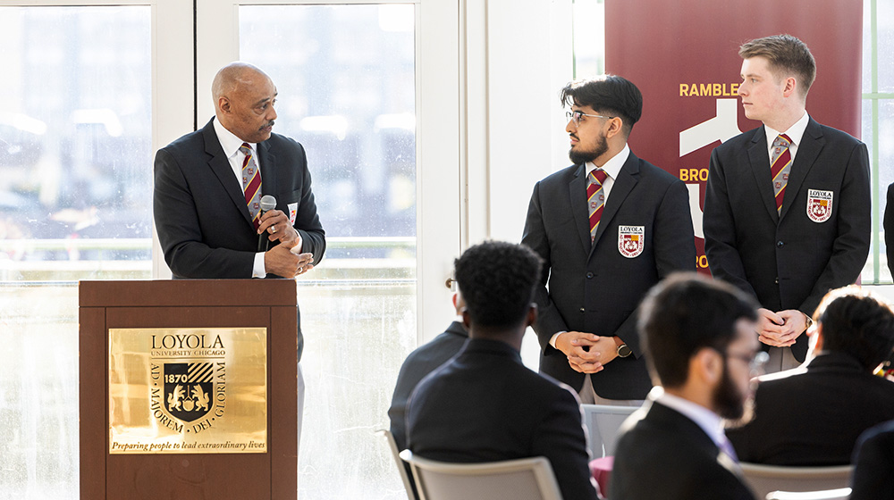 Dr. Keith Champagne speaks from a lectern to students in the Rambler Brotherhood Project.