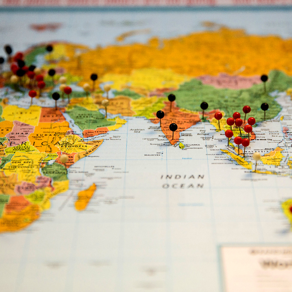 A map with several round-headed push pins sticking in it at various locations shows Africa, India, and much of Asia. A map with several round-headed push pins sticking in it at various locations shows Africa, India, and much of Asia.