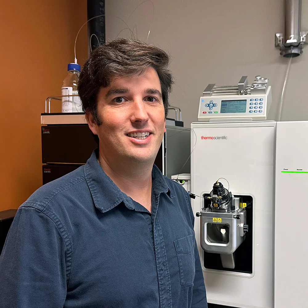 Gordon Getzinger standing in front of scientific equipment in a lab
