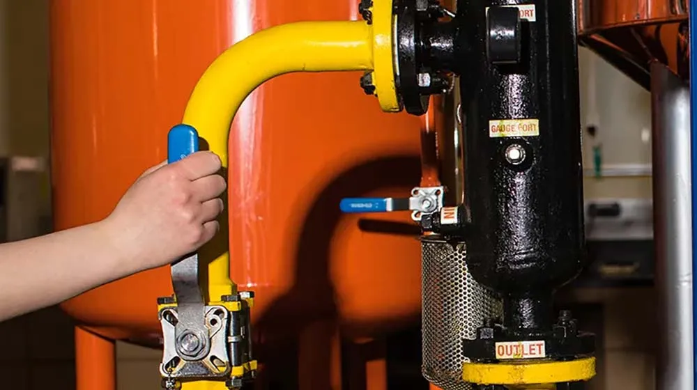 Image of pipes and a hand pulling a lever in the biodiesel lab.