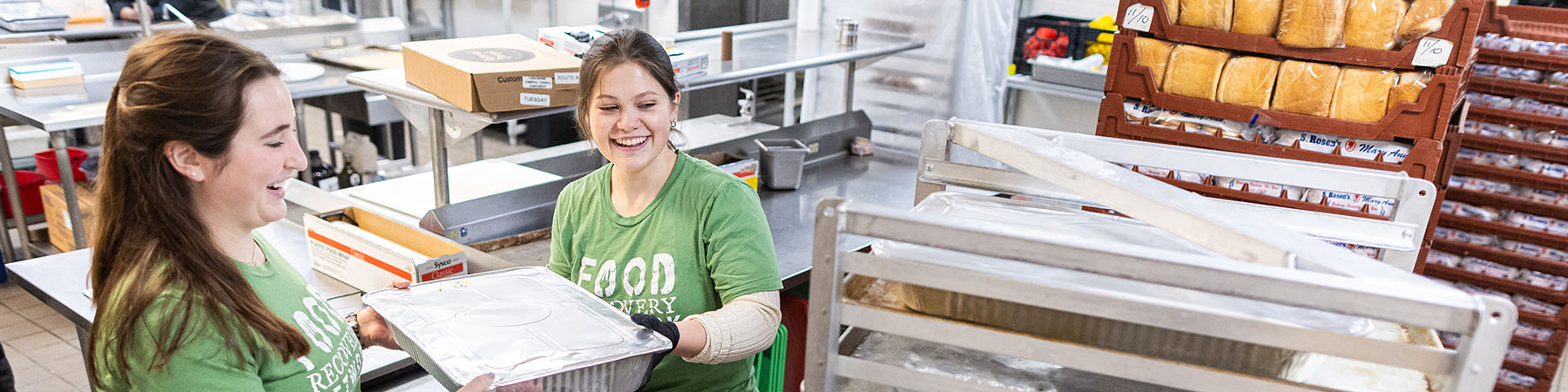 Loyola students load trays of food onto a cart