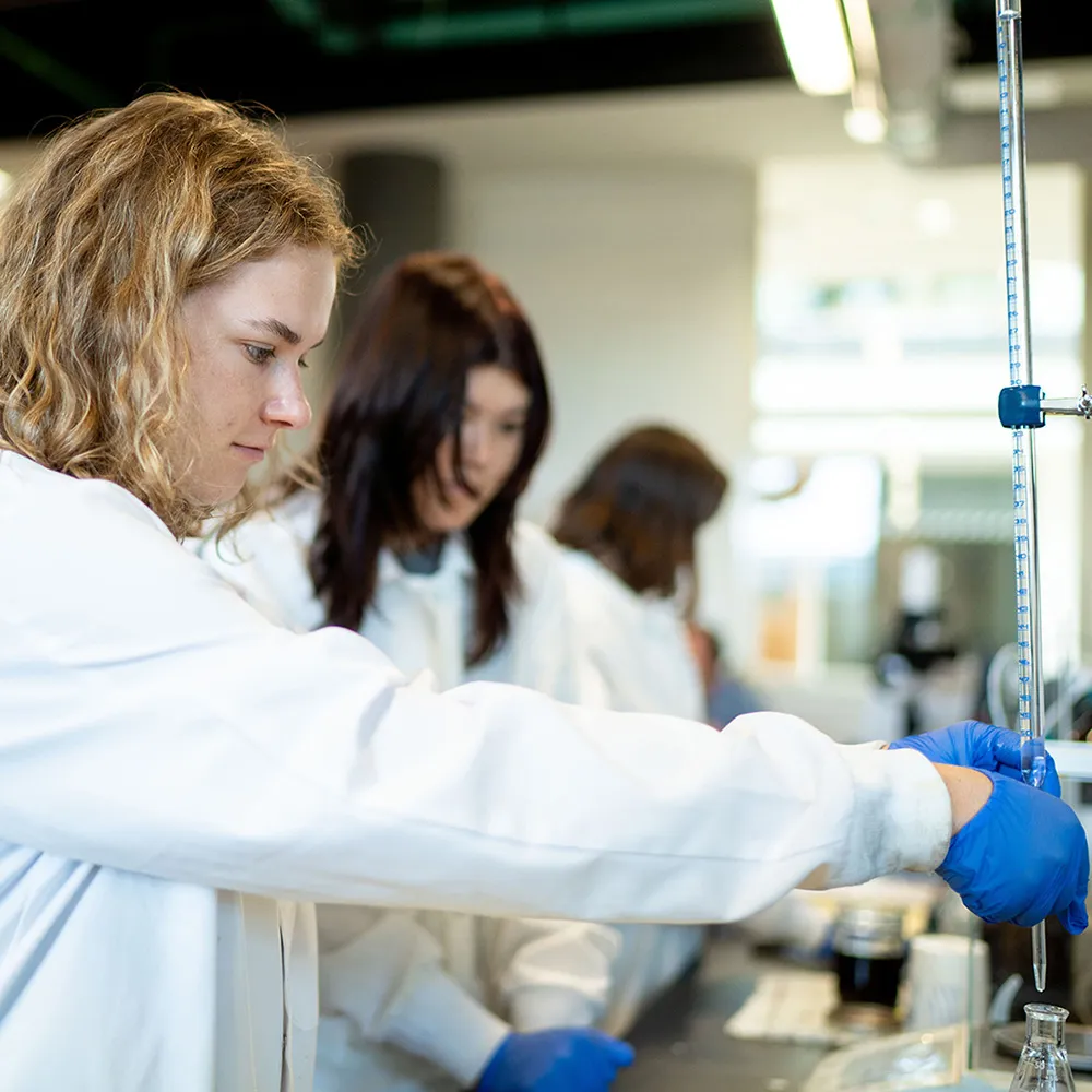 Студенты в белых халатах работают в лаборатории биодизеля