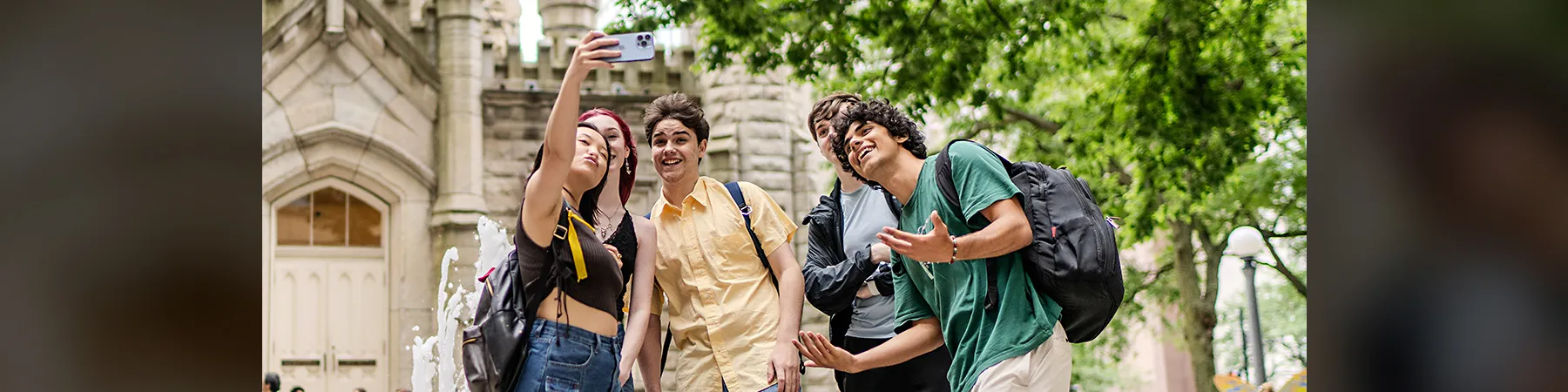 A diverse group of students take a selfie in front of the Old Water Tower Place near Michigan Avenue and the Water Tower Campus in the Chicago loop.