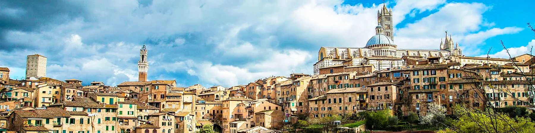 Multicolored rooftops of village homes in Rome against a dramatic blue and cloudy sky.