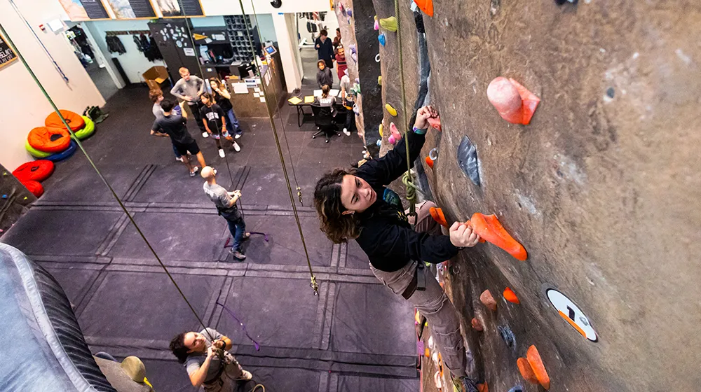 A Loyola student climbs the rock wall inside of the Halas Recreation Center at the Lakeshore Campus