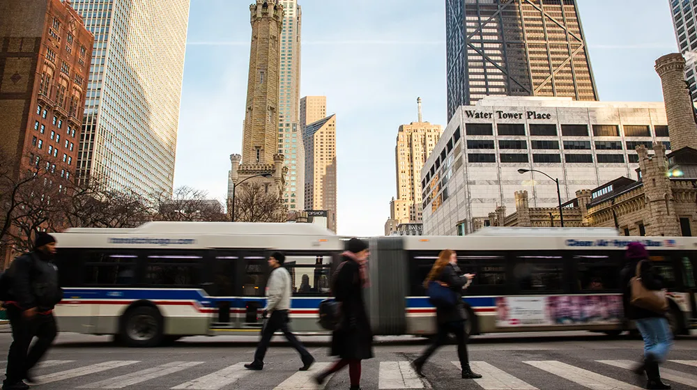 Chicagoans walk as a CTA bus drives by