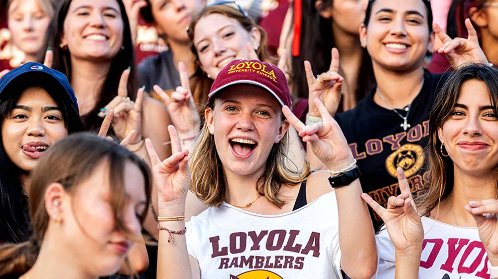 A large group of students shoulder to shoulder smile and make assorted gestures of the Loyola Spirit during Welcome Week.