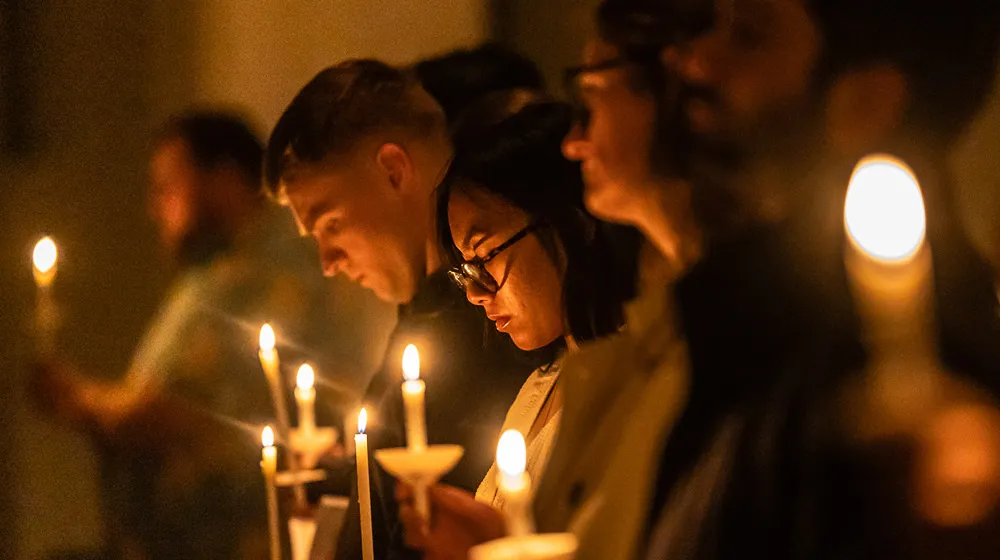 Several people hold candles during a service in the Madonna Della Strada Chapel. The amber glow of the lighted candles fills the space. Several people hold candles during a service in the Madonna Della Strada Chapel. The amber glow of the lighted candles fills the space.