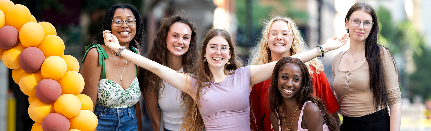 A group of students stand near balloons at the water-tower-campus-block-party.