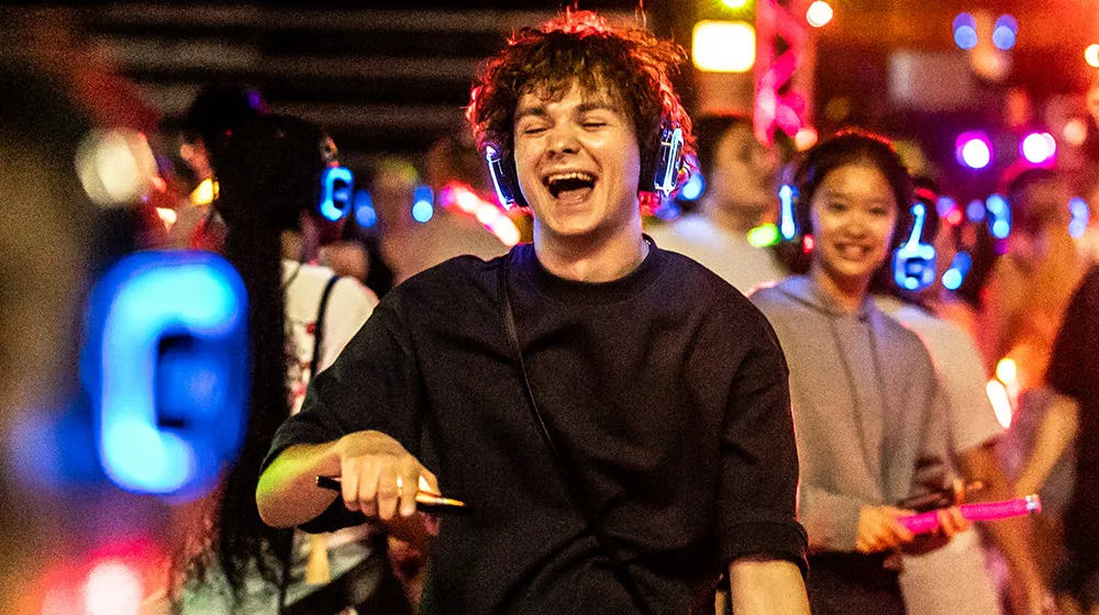 A student dances at the Silent Disco event during Welcome Week. All of the students are wearing multi-colored LED headphones that light up the dark room.