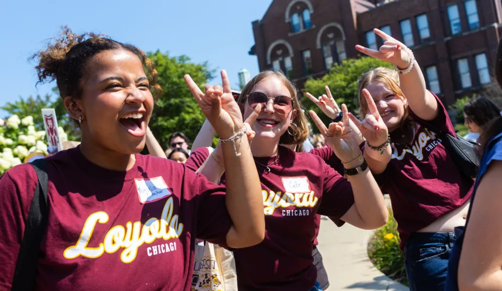 Students in Loyola t-shirts sharing the wolf sign with each other at Welcome Week. Students in Loyola t-shirts sharing the wolf sign with each other at Welcome Week.