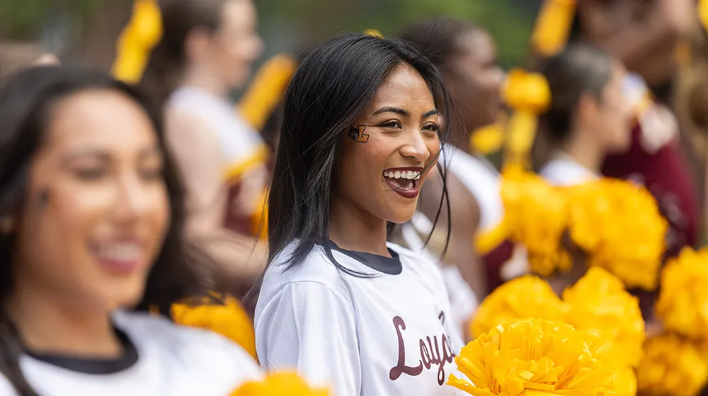 A portrait of a smiling cheerleader in the crowd at Welcome Week.