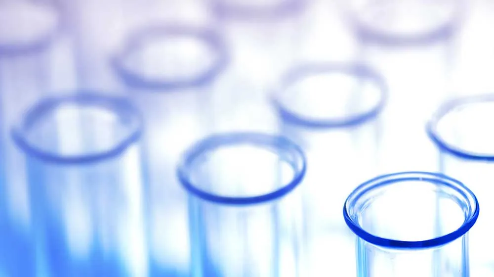 A close-up perspective of multiple glass test tubes that reflect blue and violet lighting. A close-up perspective of multiple glass test tubes that reflect blue and violet lighting.