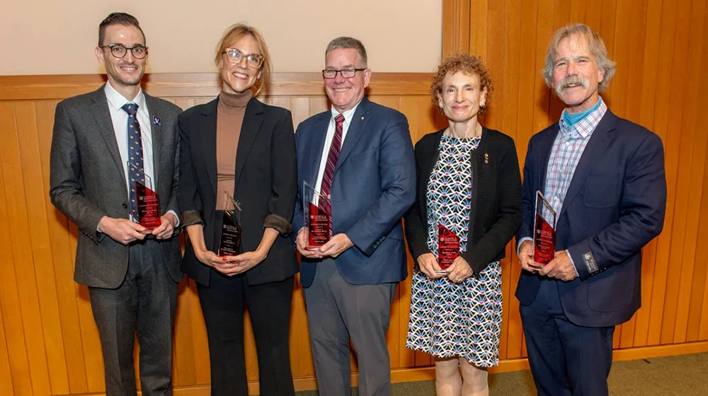 The five Stritch Alumni of the Year Award winners smiling and each holding a glass trophy.