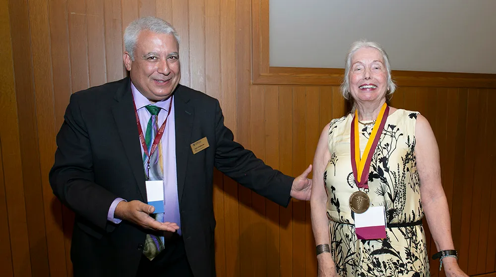 Stritch Dean Sam Marzo smiling and standing next to Dr. Eva Bading who is smiling and proudly wearing the Stritch Medal
