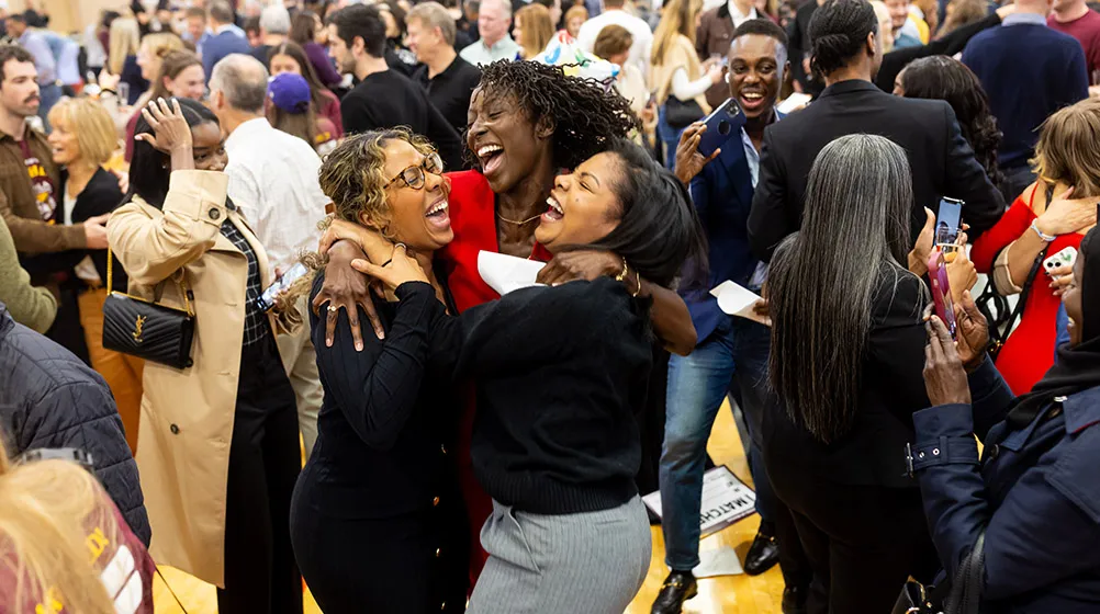 Three students jumping for joy in the middle of the crowd at Match Day.