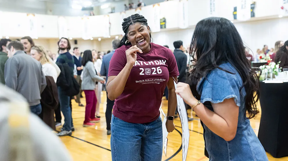 A student wearing a maroon Match Day 2026 t-shirt jumps for joy