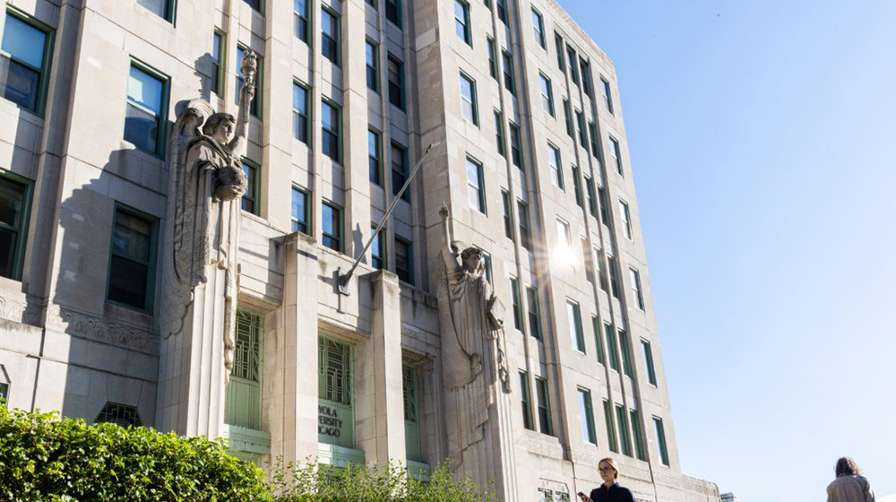 Loyola University Chicago building façade with statues flanking the entrance under clear sky