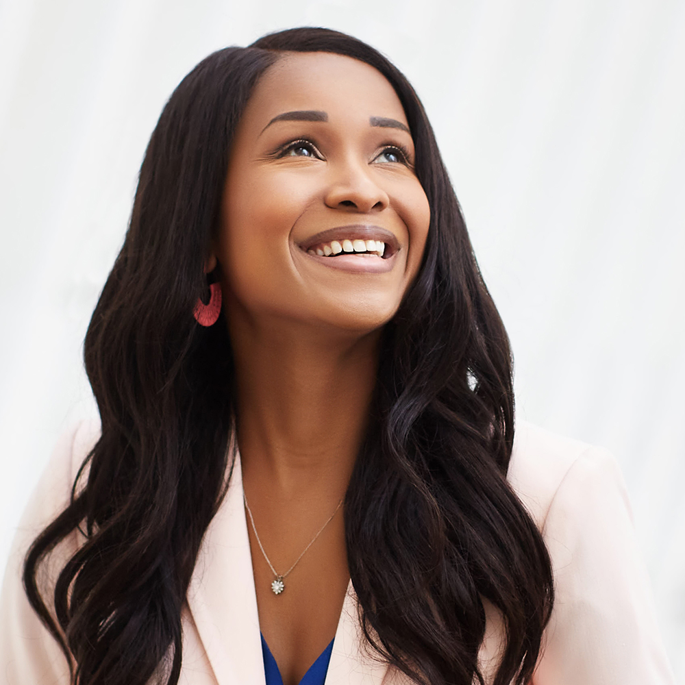 Smiling woman with long dark hair looking upward, photographed against a neutral background