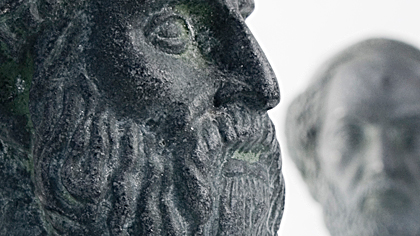 Close-up of a stone bust with another statue blurred in the background.