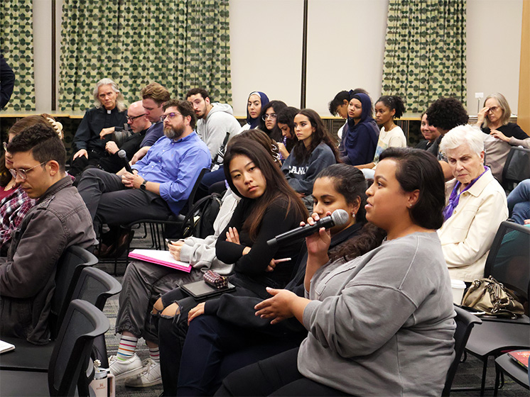 Audience member speaking into a microphone during a group discussion in a classroom setting