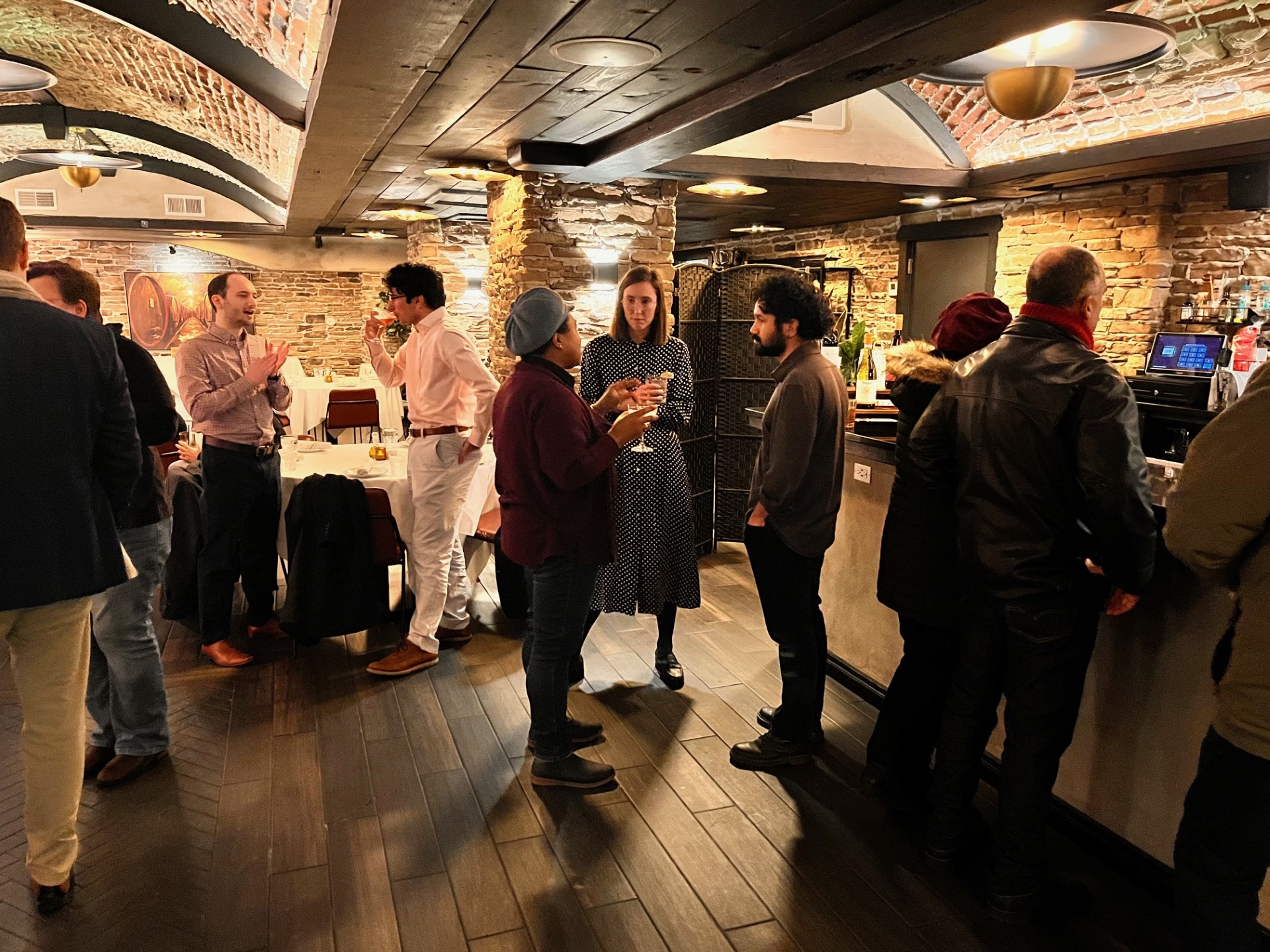 People socializing in a restaurant with exposed brick walls and warm lighting
