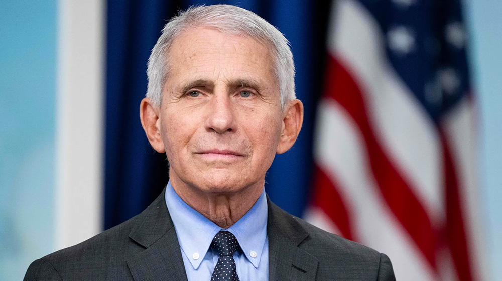 Portrait of Dr. Fauci in a suit and tie with a U.S. flag in the background