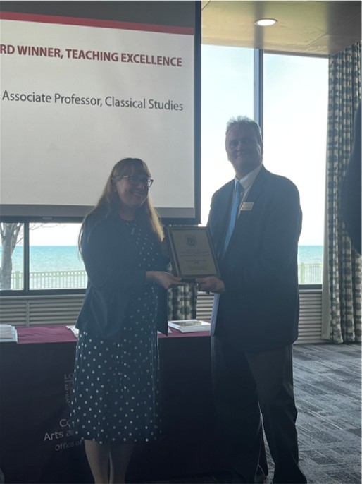 Person receiving a teaching excellence award during an indoor event