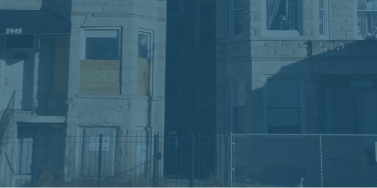 Boarded-up residential building with a fence in front, tinted blue.