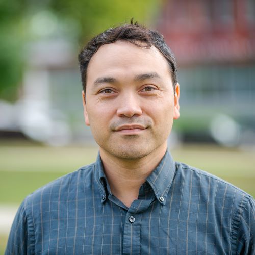 Man outdoors with a blurred background, facing the camera.