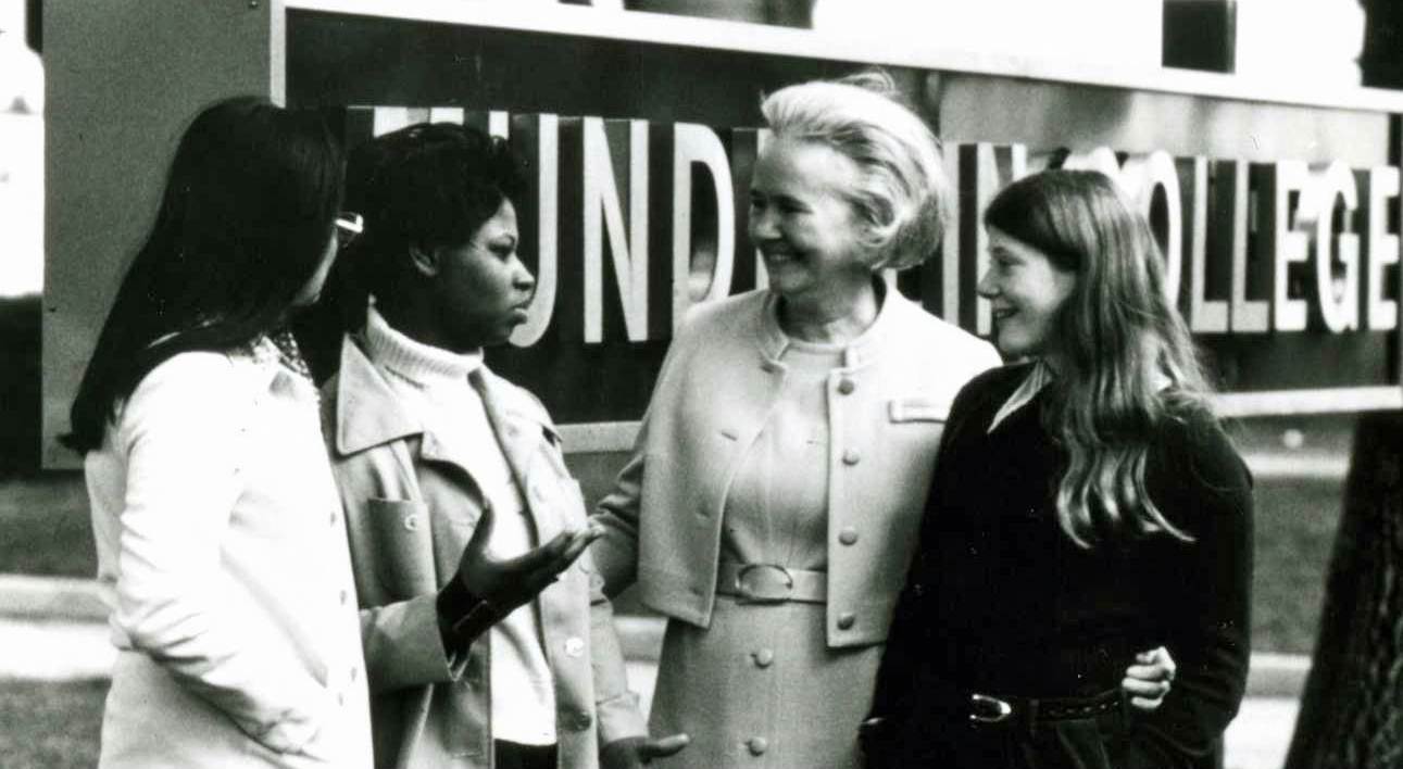 Sister Ann Ida Gannon standing with students in front of the Mundelein College sign