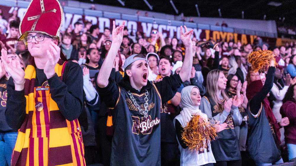 Fans in LUC maroon and gold cheer at a basketball game