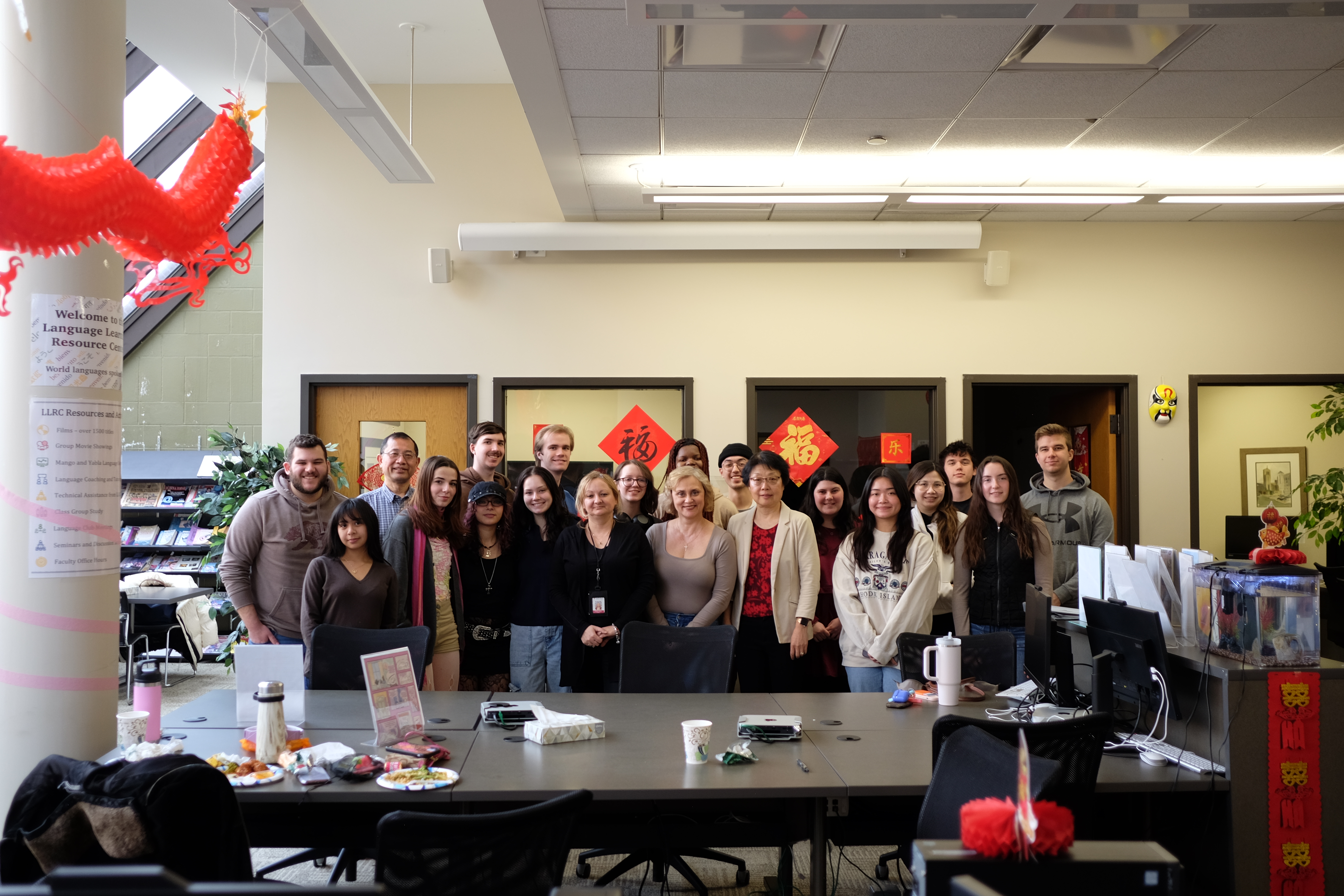 Group of students and staff posing together in a classroom decorated with Lunar New Year decorations.