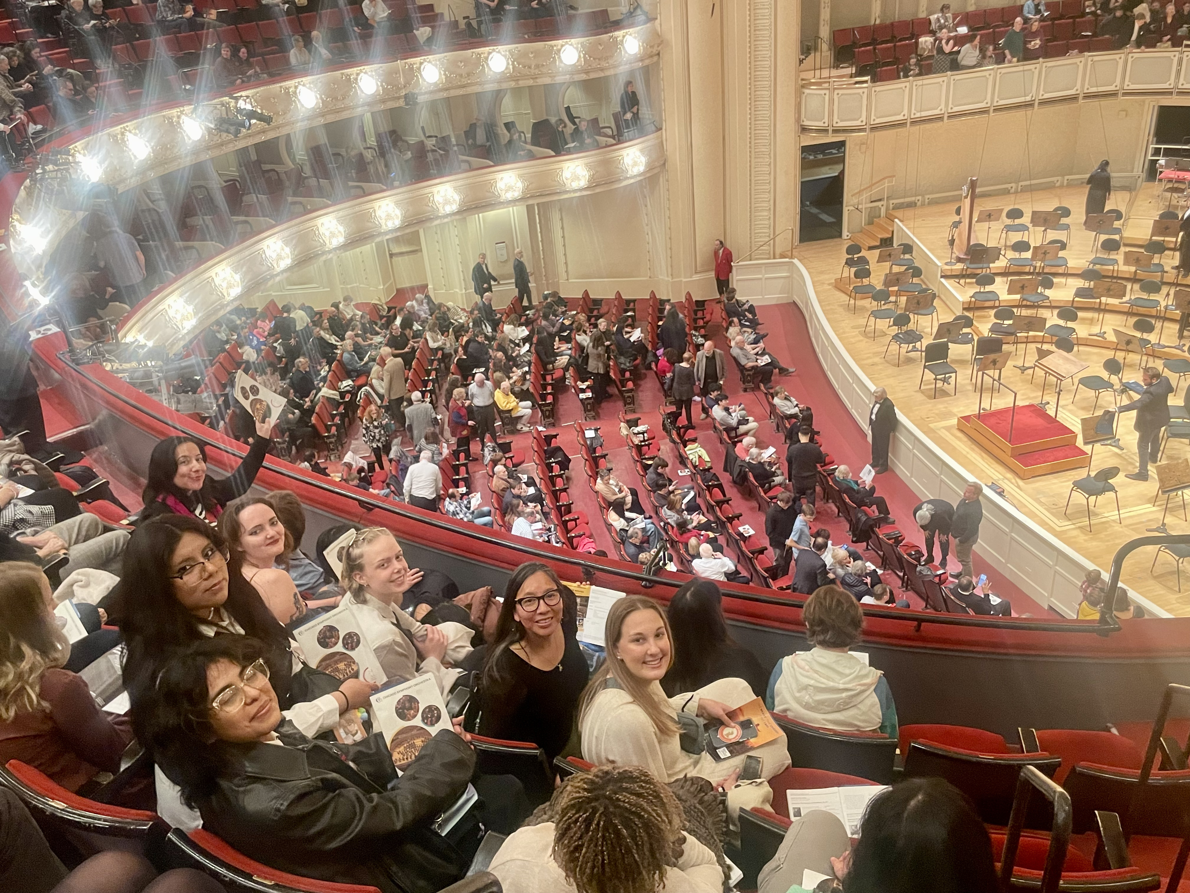 Audience seated in a theater balcony overlooking a concert hall stage before a performance of Don Quixote.