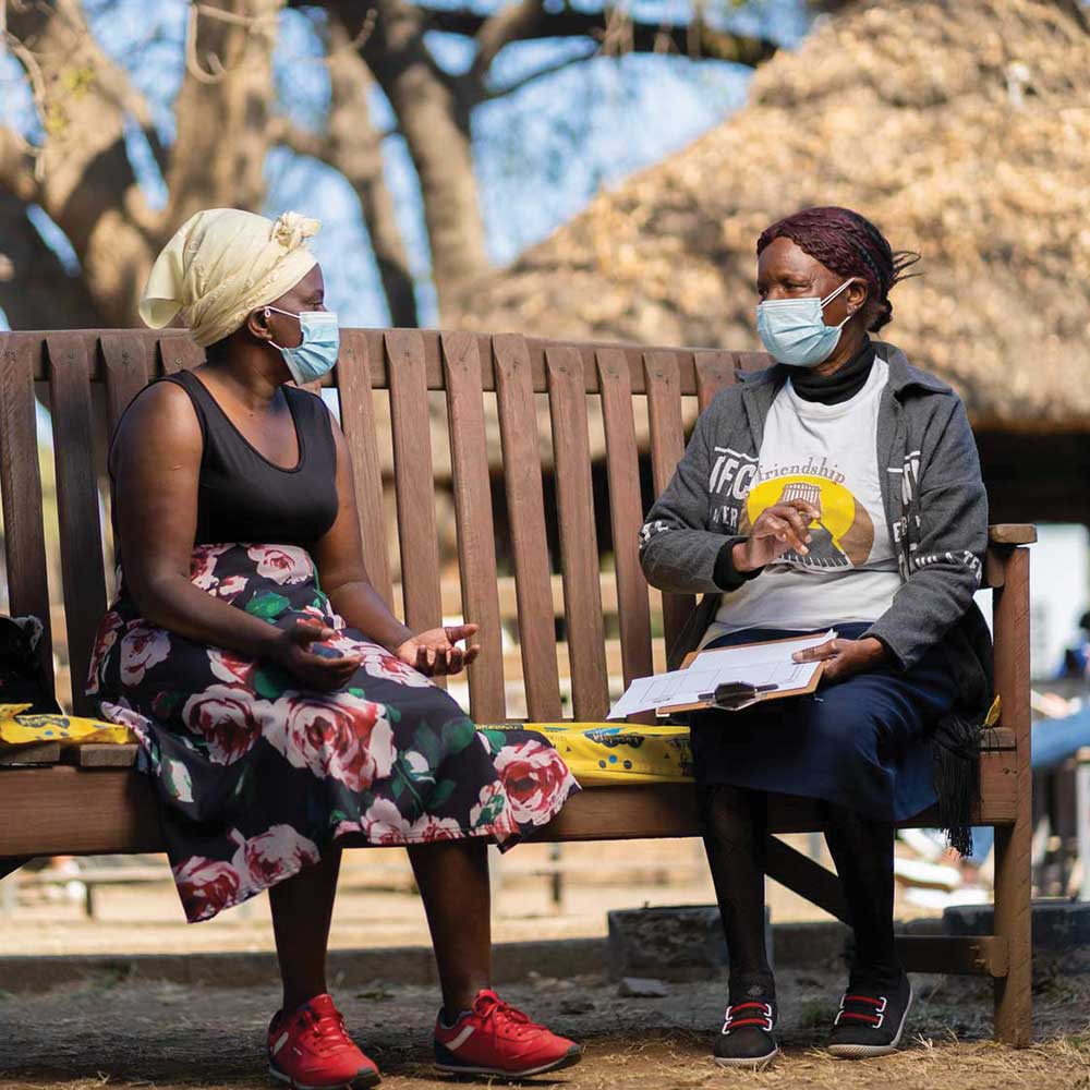 Friendship Bench Ambuya Utano (Community Grandmother) having a problem-solving therapy session on the Friendship Bench in Harare, Zimbabwe.