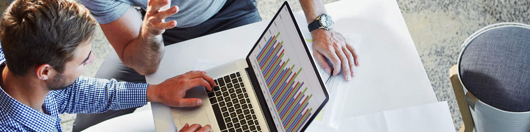 Father and son at a computer reviewing a financial graph