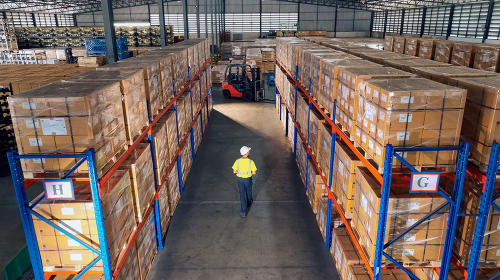 Supply chain warehouse with a single worker waling the aisle