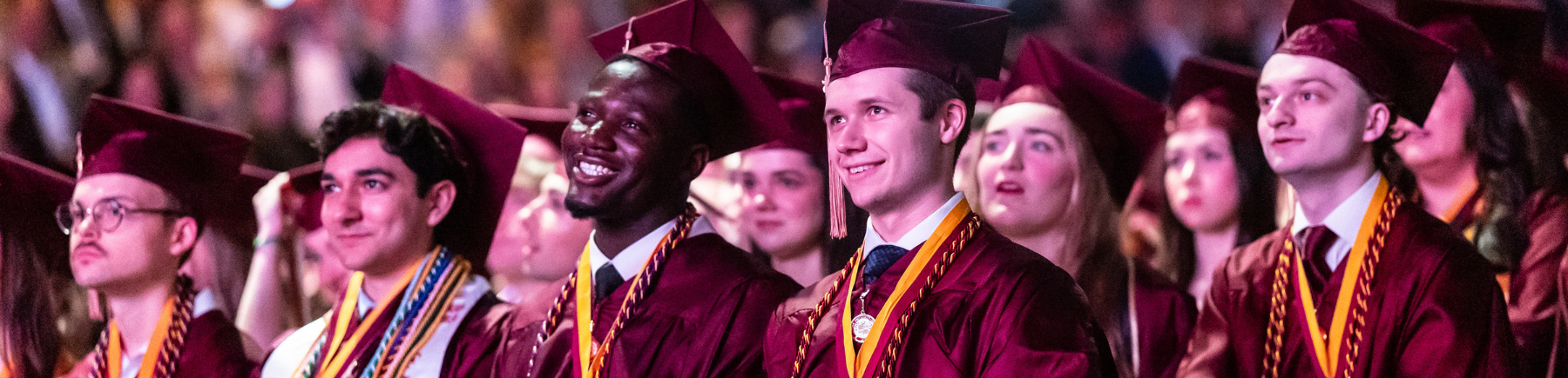 Photo of graduates in maroon caps and gowns at their commencement