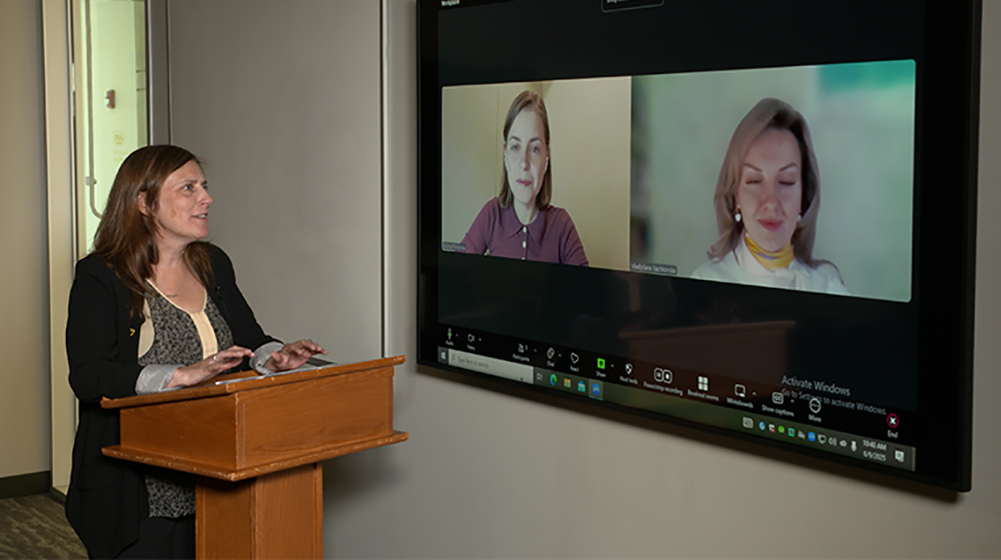 Staff member on a video call at a desk with dual monitors
