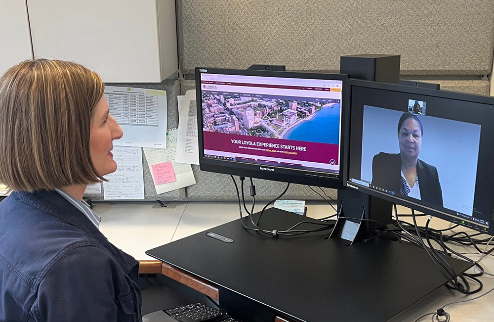 Staff member on a video call at a desk with dual monitors