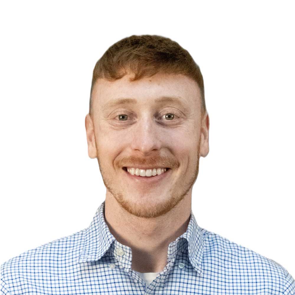 Professional headshot of a smiling man with short hair and light facial hair on a light background
