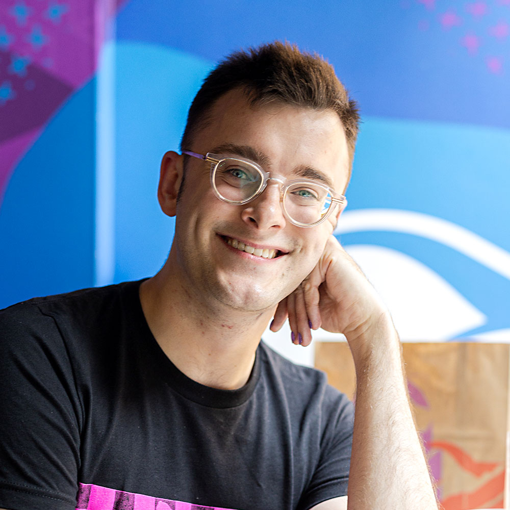 Smiling man with glasses resting his head on his hand at a Taco Bell
