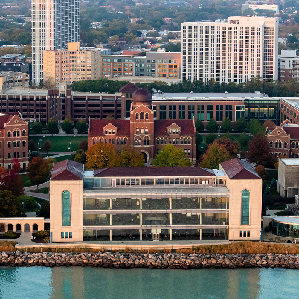 Aerial view of Loyola University Chicago’s Lake Shore Campus, featuring Mundelein Center and other academic buildings along Lake Michigan, with autumn