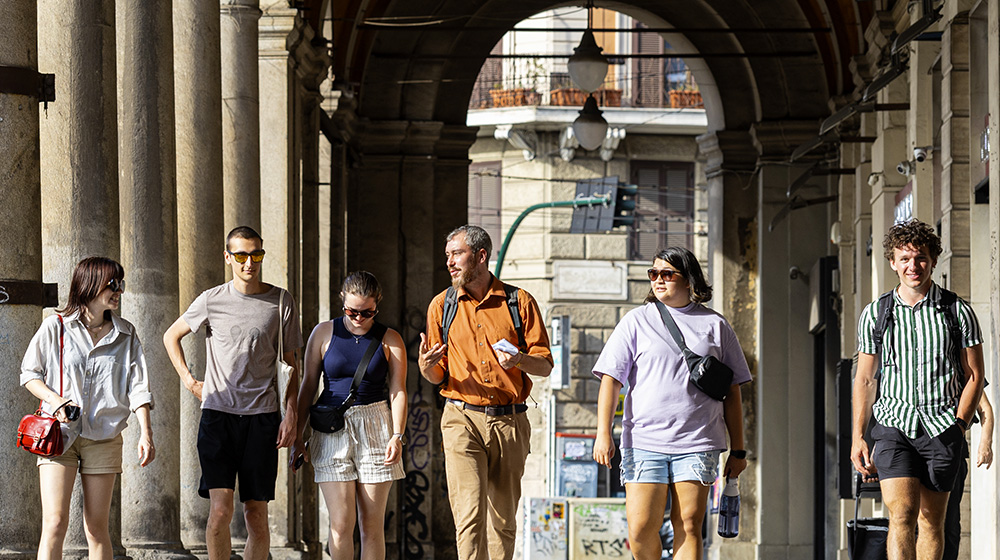 A group of student and an instructor walk together under archways in Rome